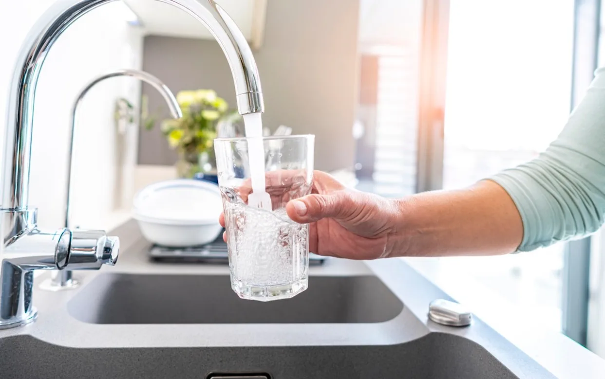 Person filling glass with tap water